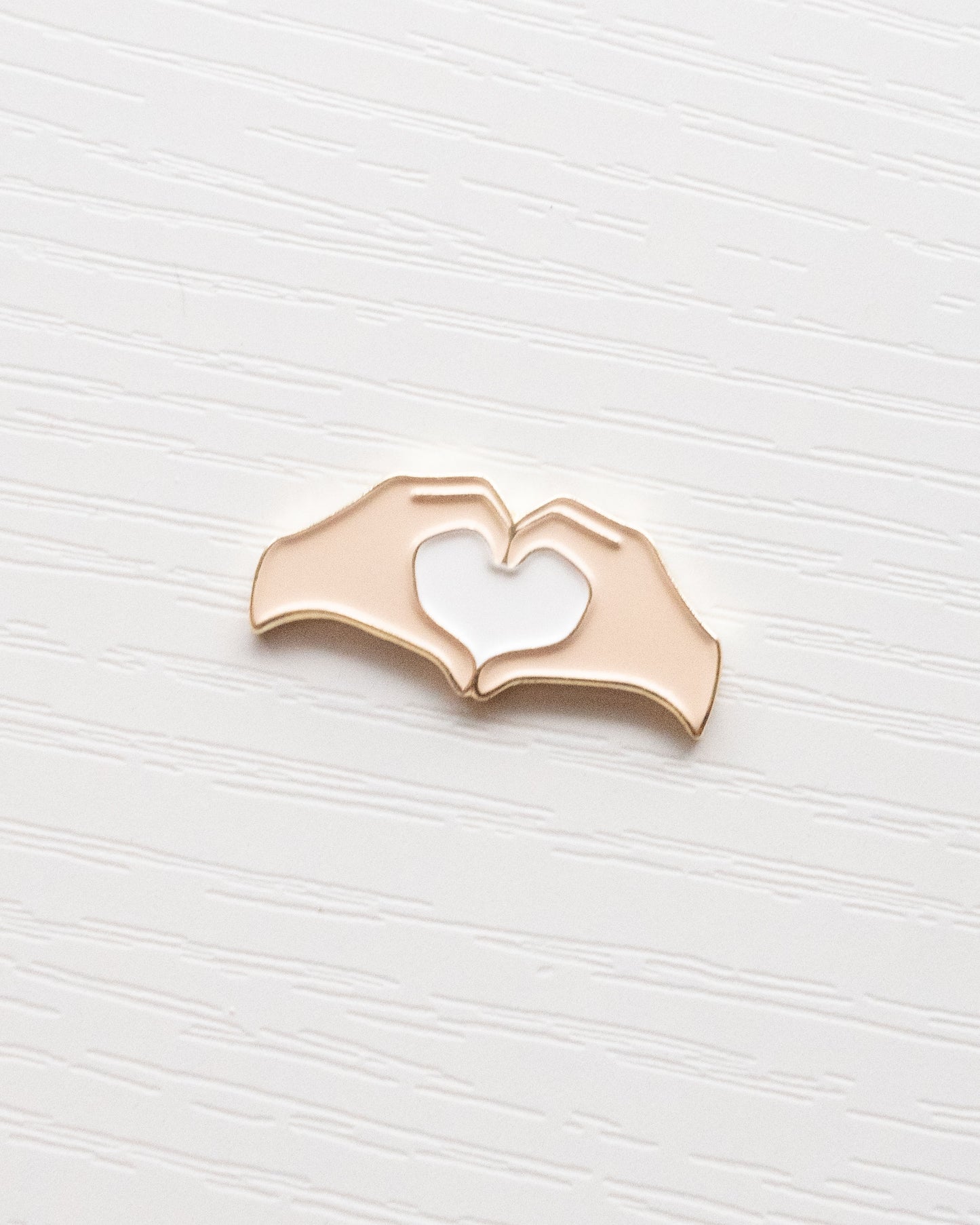 Heart Hands Embroidery Needle Minder close up on a white wooden background