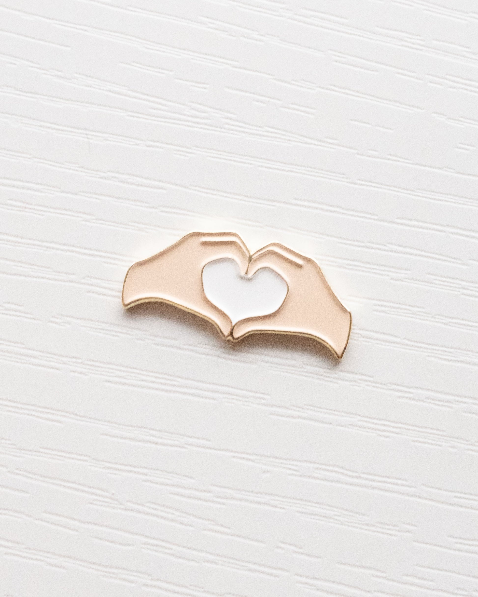 Heart Hands Embroidery Needle Minder close up on a white wooden background