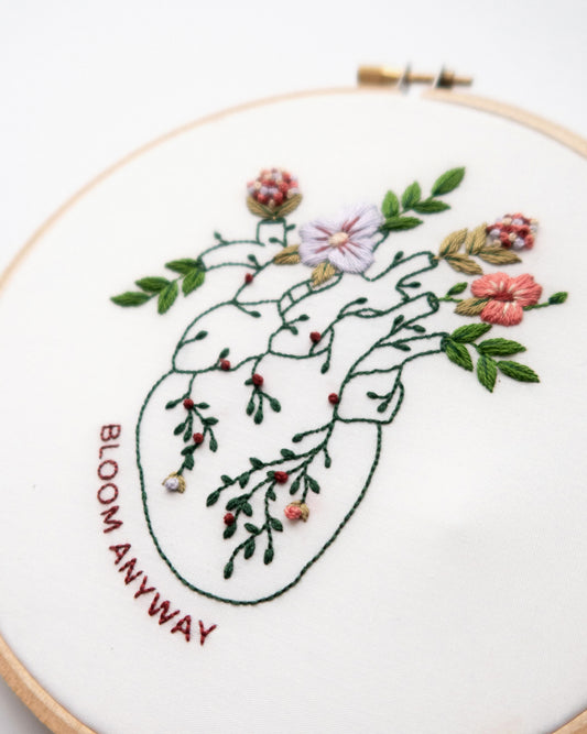 Bloom floral heart anatomy hand embroidery pattern for mental health with pink, purple and red flowers and green leaves close up