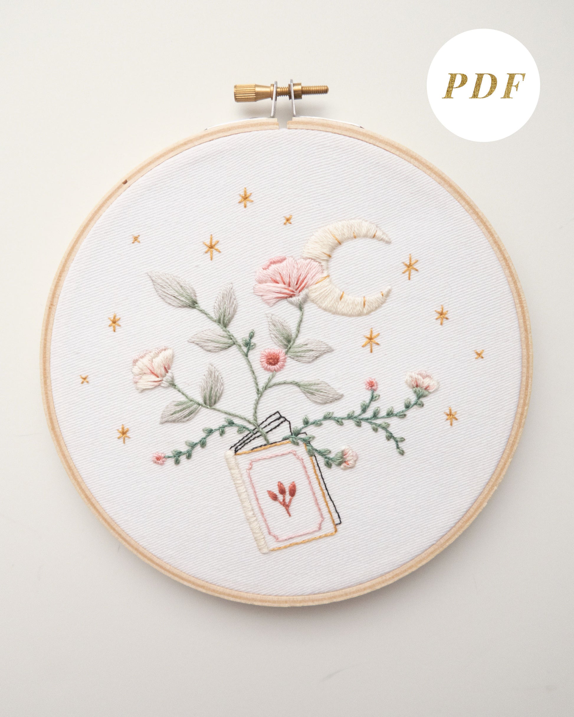 Embroidery pattern with open floral book with garden flowers and branches growing from open pages with stars and moon hand embroidery kit on embroidery hoop with boho dried florals