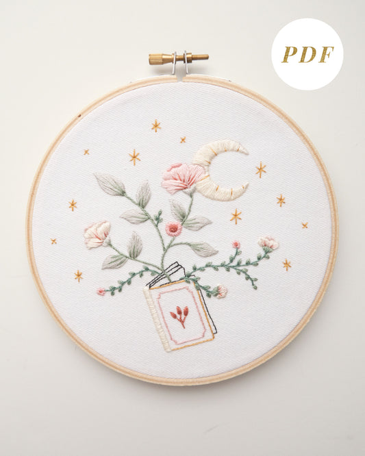 Embroidery pattern with open floral book with garden flowers and branches growing from open pages with stars and moon hand embroidery kit on embroidery hoop with boho dried florals