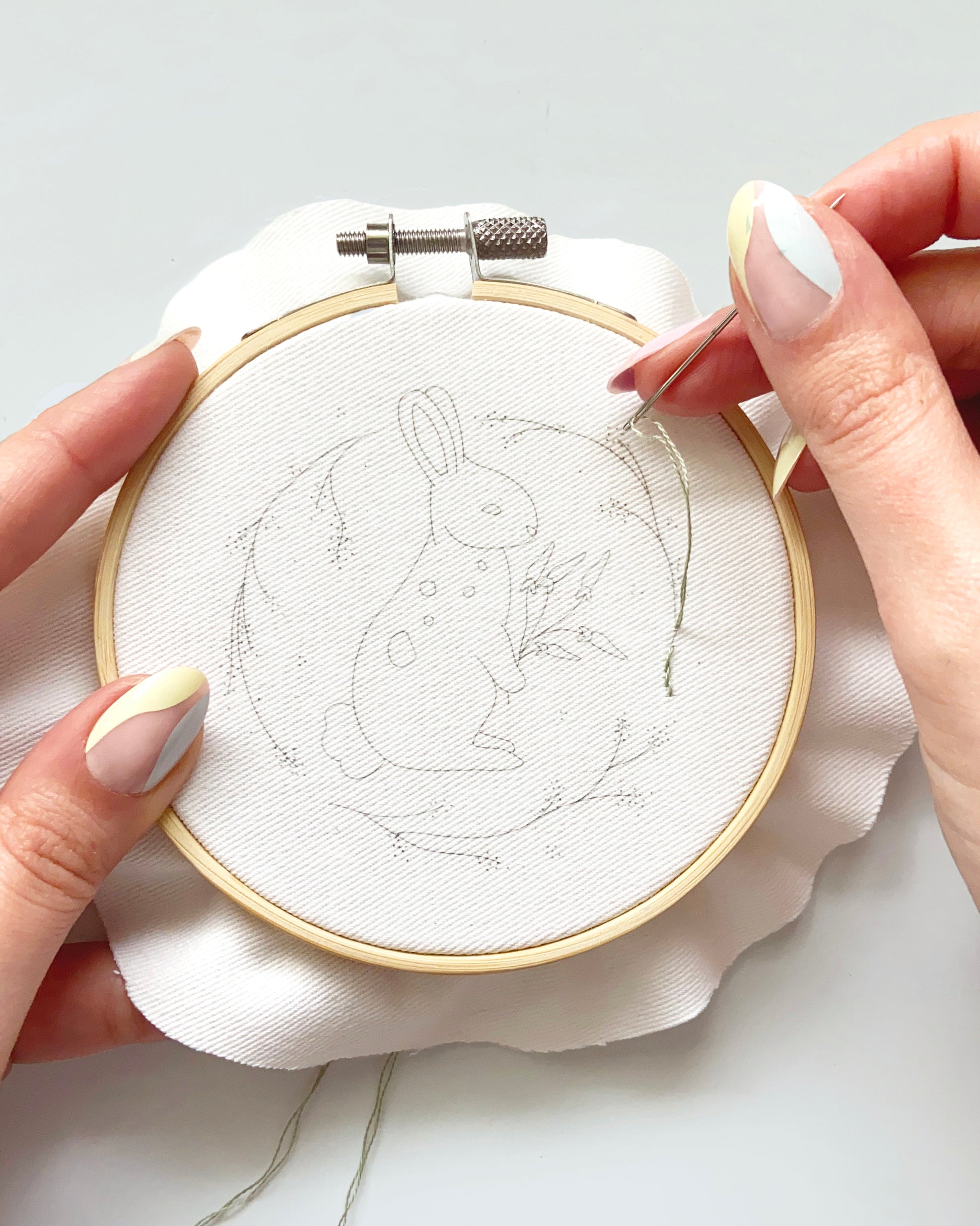Spring Bunny Embroidery Pattern traced pattern in hoop with hands and embroidery needle ready to embroider