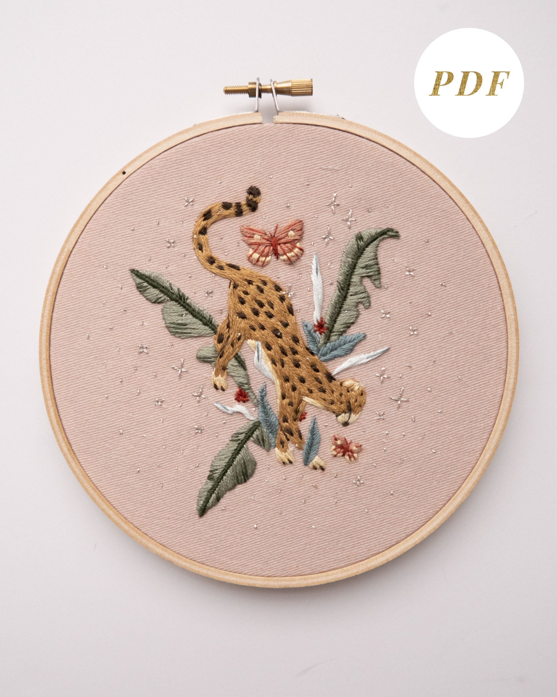 Cheetah in jungle hand embroidery pattern on light pink fabric, green jungle leaves, pink butterflies and silver stars