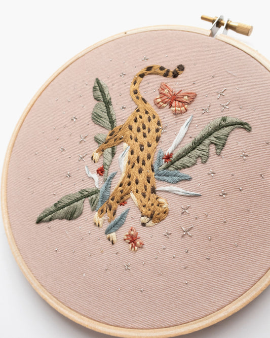 Cheetah in jungle hand embroidery pattern on light pink fabric, green jungle leaves, pink butterflies and silver stars, completed close up of details