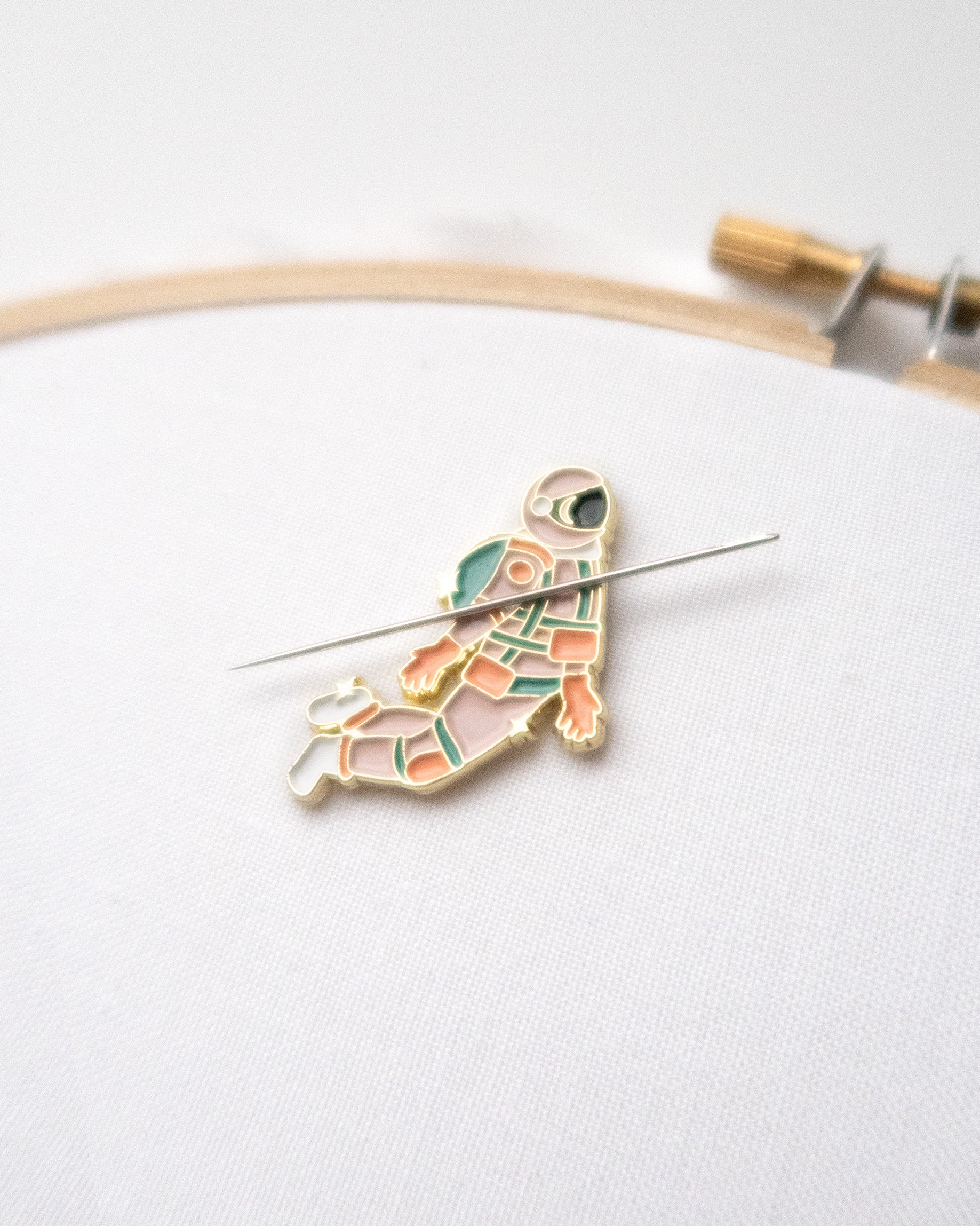 Pink and gold astronaut enamel needle minder or needle nanny on hand embroidery hoop with embroidery needle