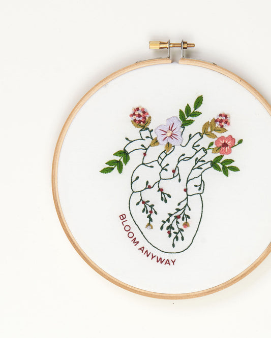 Bloom floral heart anatomy hand embroidery kit for mental health with pink, purple and red flowers and green leaves close up finished