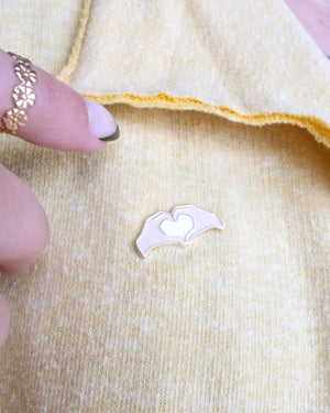Heart Hands Embroidery Needle Minder on a yellow piece of fabric with hands