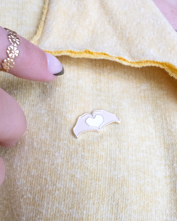Heart Hands Embroidery Needle Minder on a yellow piece of fabric with hands