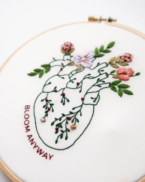 Bloom floral heart anatomy hand embroidery pattern for mental health with pink, purple and red flowers and green leaves close up