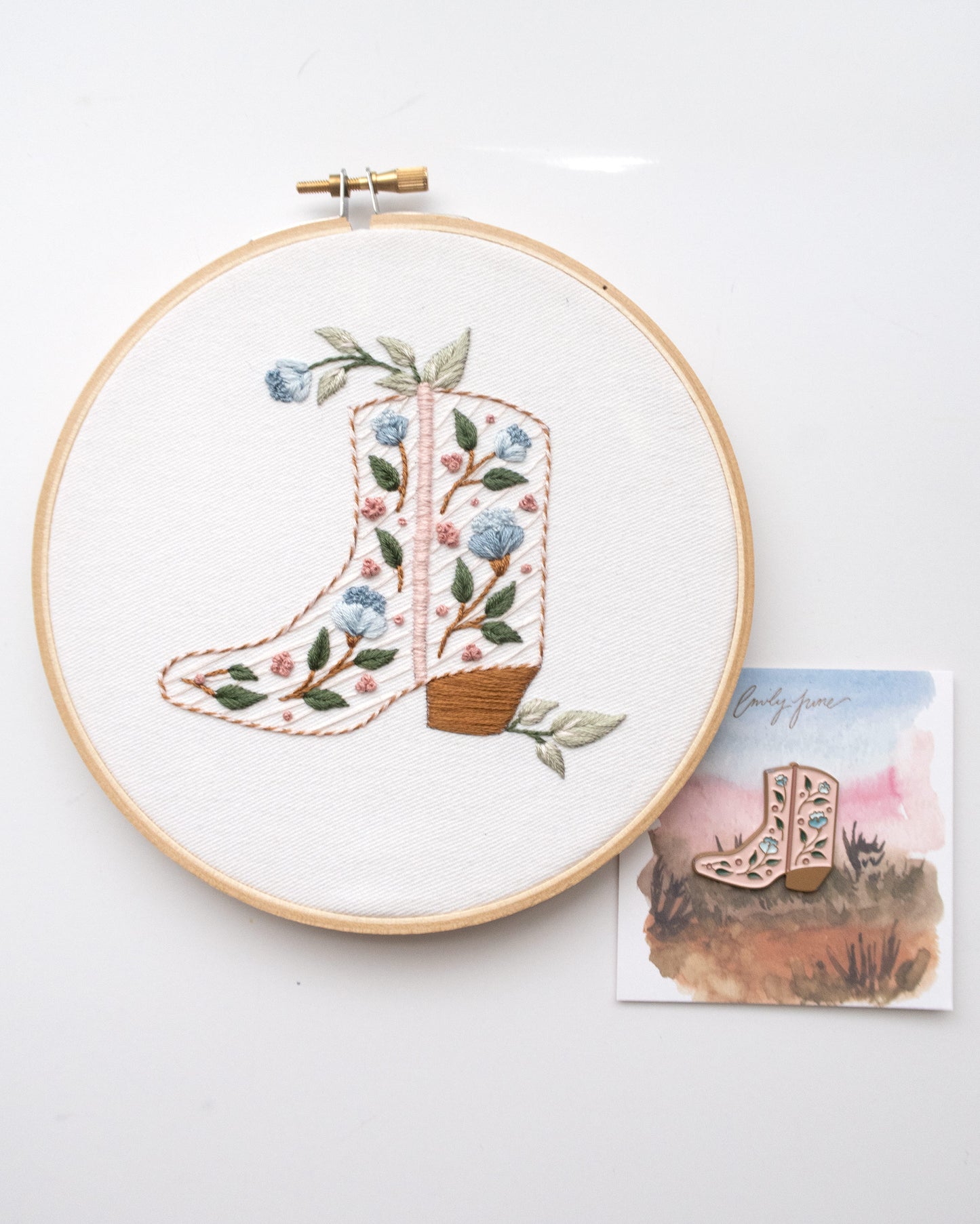Southwest themed embroidery bundle with embroidery kit that includes wood embroidery hoop, printed embroidery fabric, embroidery needle, embroidery floss, and embroidery guide, and pink cowboy boot enamel needle nanny or needle minder