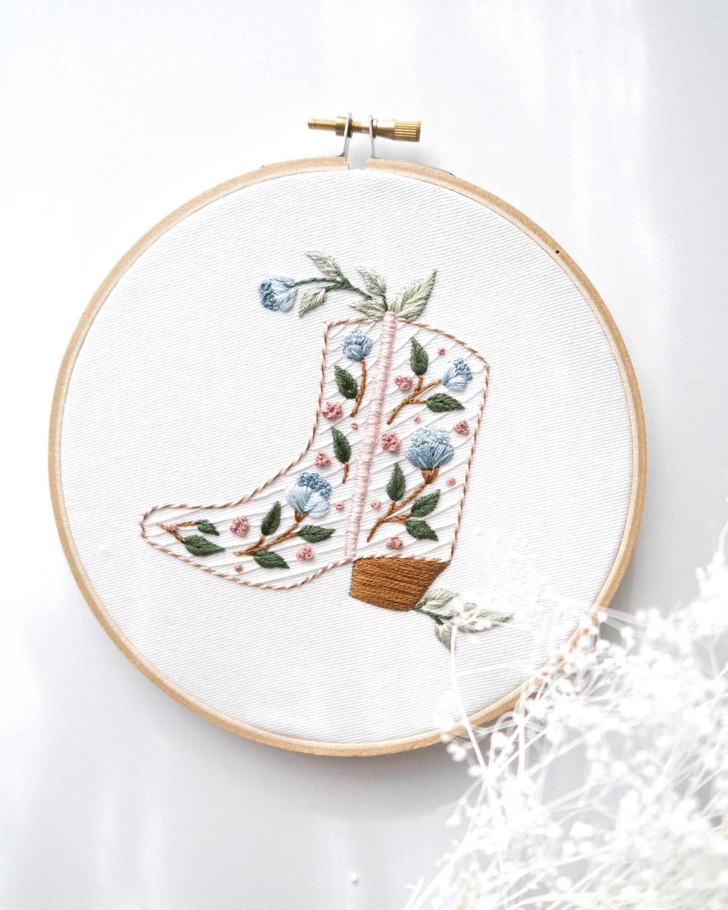 Floral cowboy boot hand embroidery kit with pink and blue flowers and light green leaves with white flowers in foreground