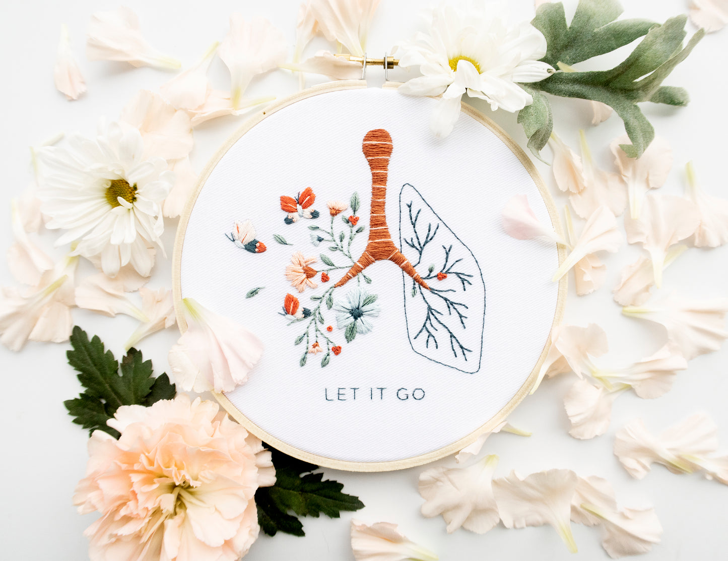 Floral anatomy hand embroidery pattern featuring floral lung with Let It Go mental health quote for mental health embroidery and beginner friendly embroidery with pink flowers green plants on white background