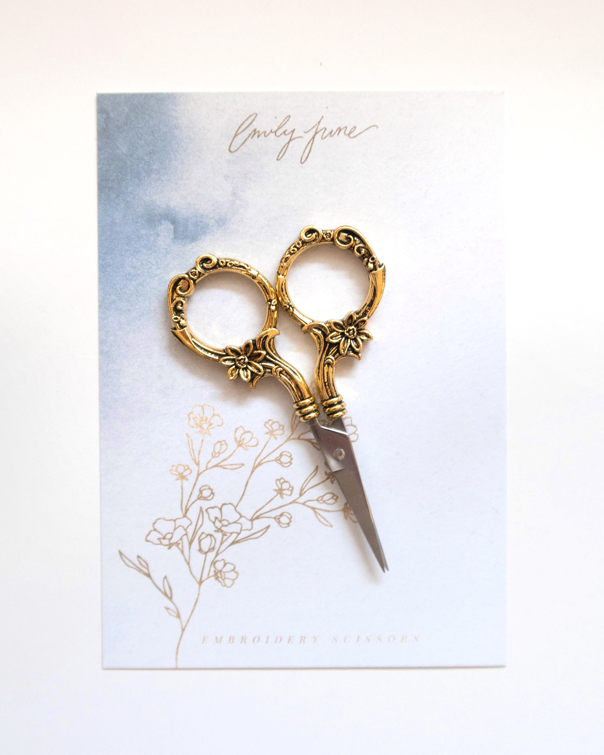 Small vintage gold sewing scissors or embroidery scissors on watercolor packaging