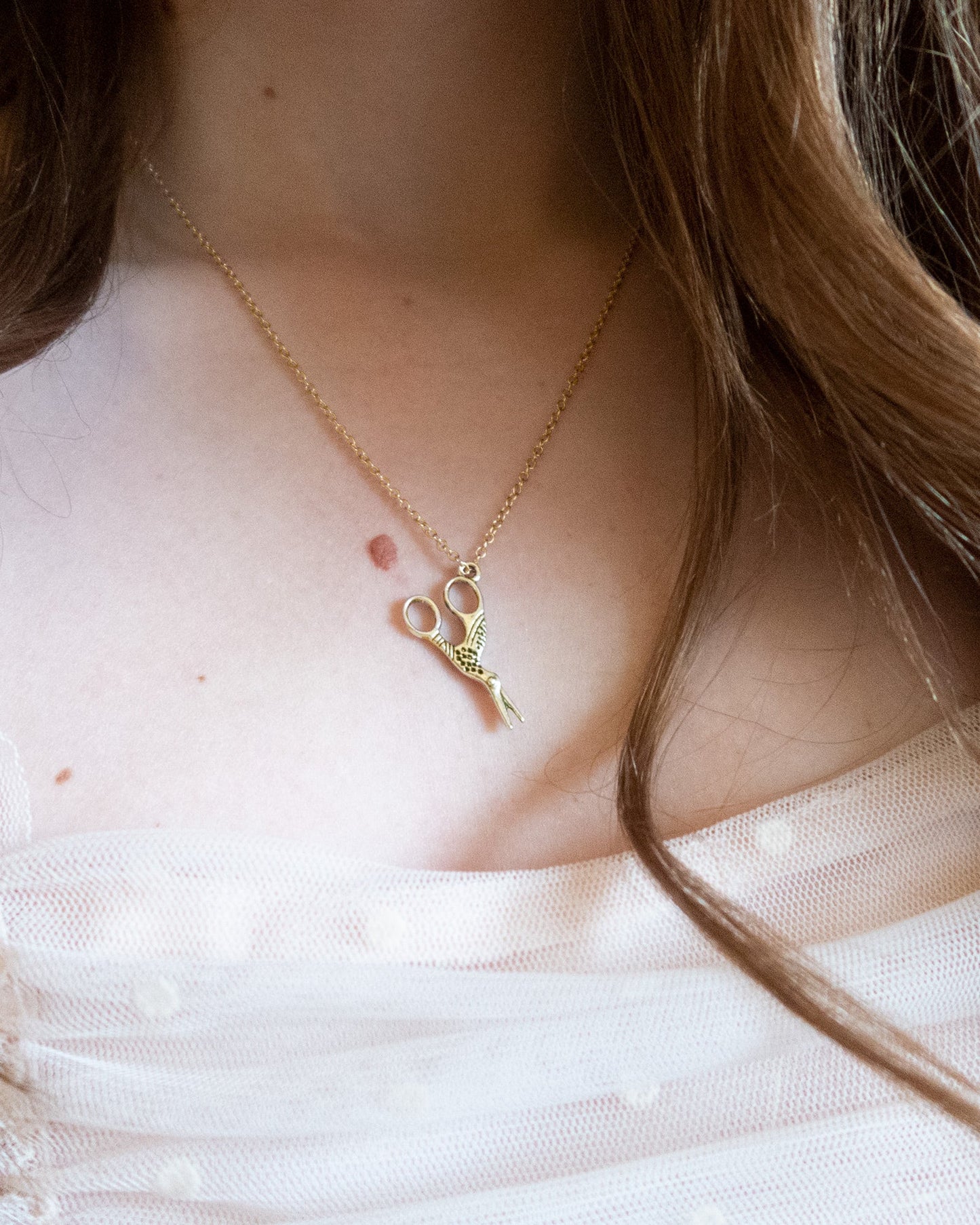 Gold crane scissor necklace on brunette with boho styling, embroidery jewelry