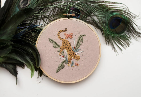 Cheetah in jungle hand embroidery pattern on light pink fabric, green jungle leaves, pink butterflies and silver stars with peacock feather