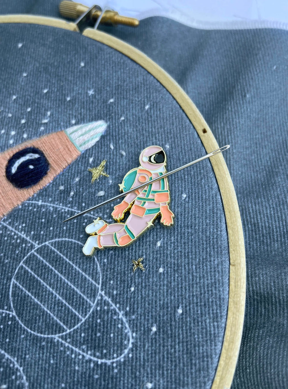 Pink and gold astronaut enamel needle minder or needle nanny on hand embroidery hoop with embroidery needle